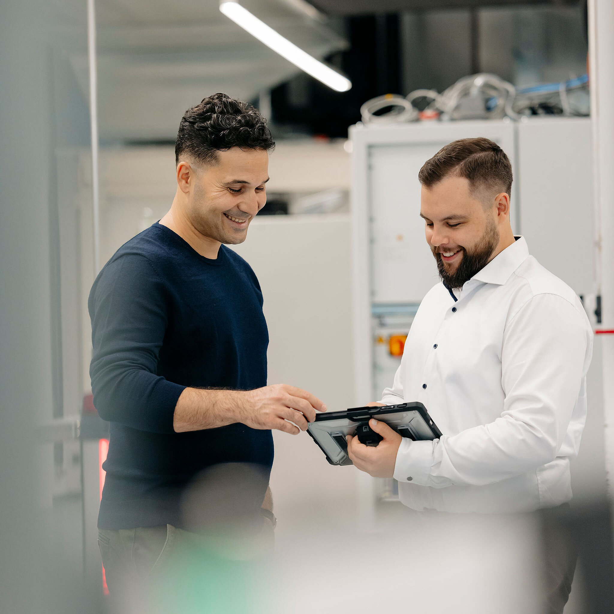 Zwei Mitarbeiter von Silver Atena besprechen technische Prüfergebnisse auf einem Tablet im Labor.