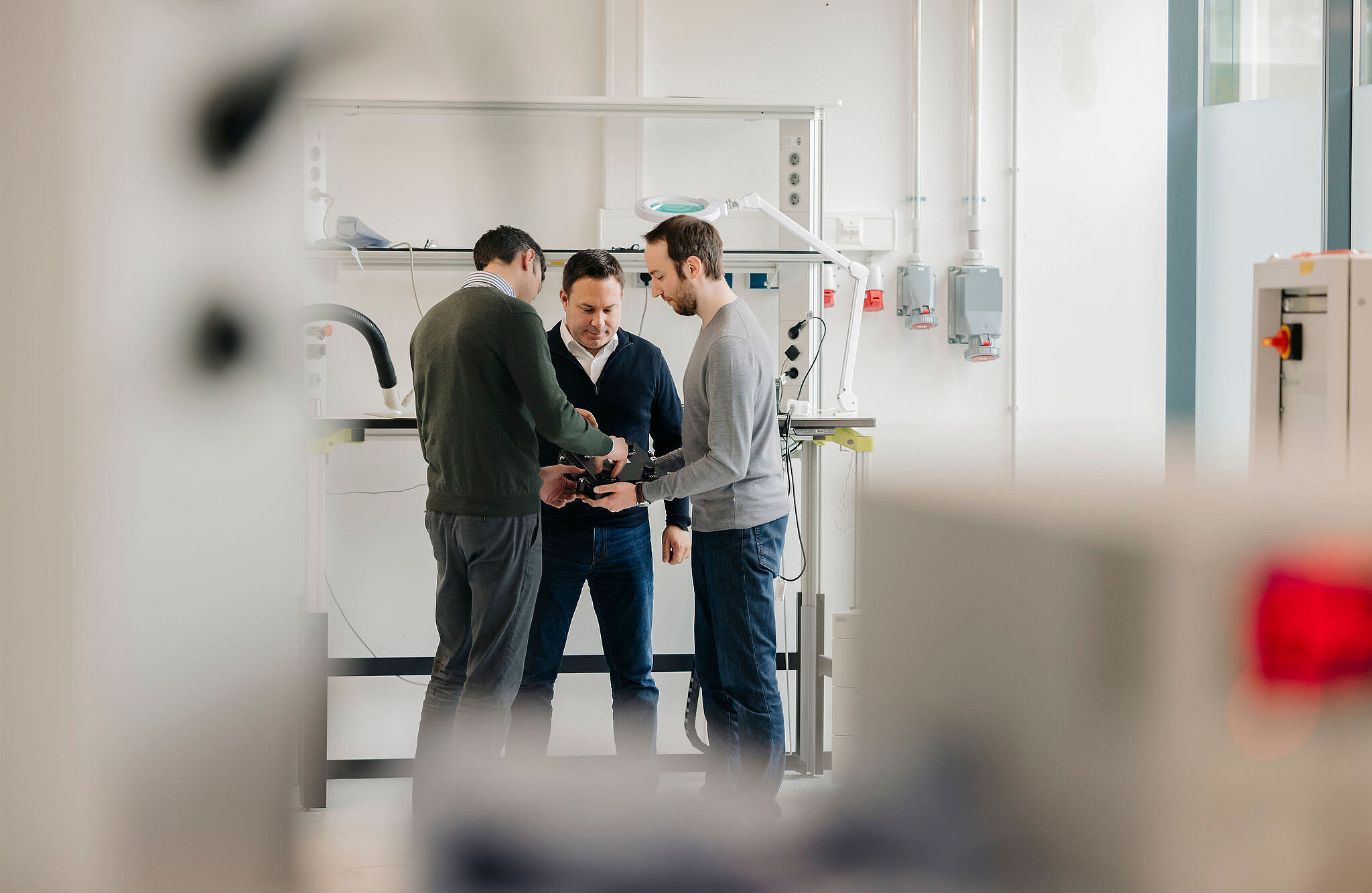 Drei Ingenieure von Silver Atena besprechen eine technische Baugruppe im Entwicklungslabor.