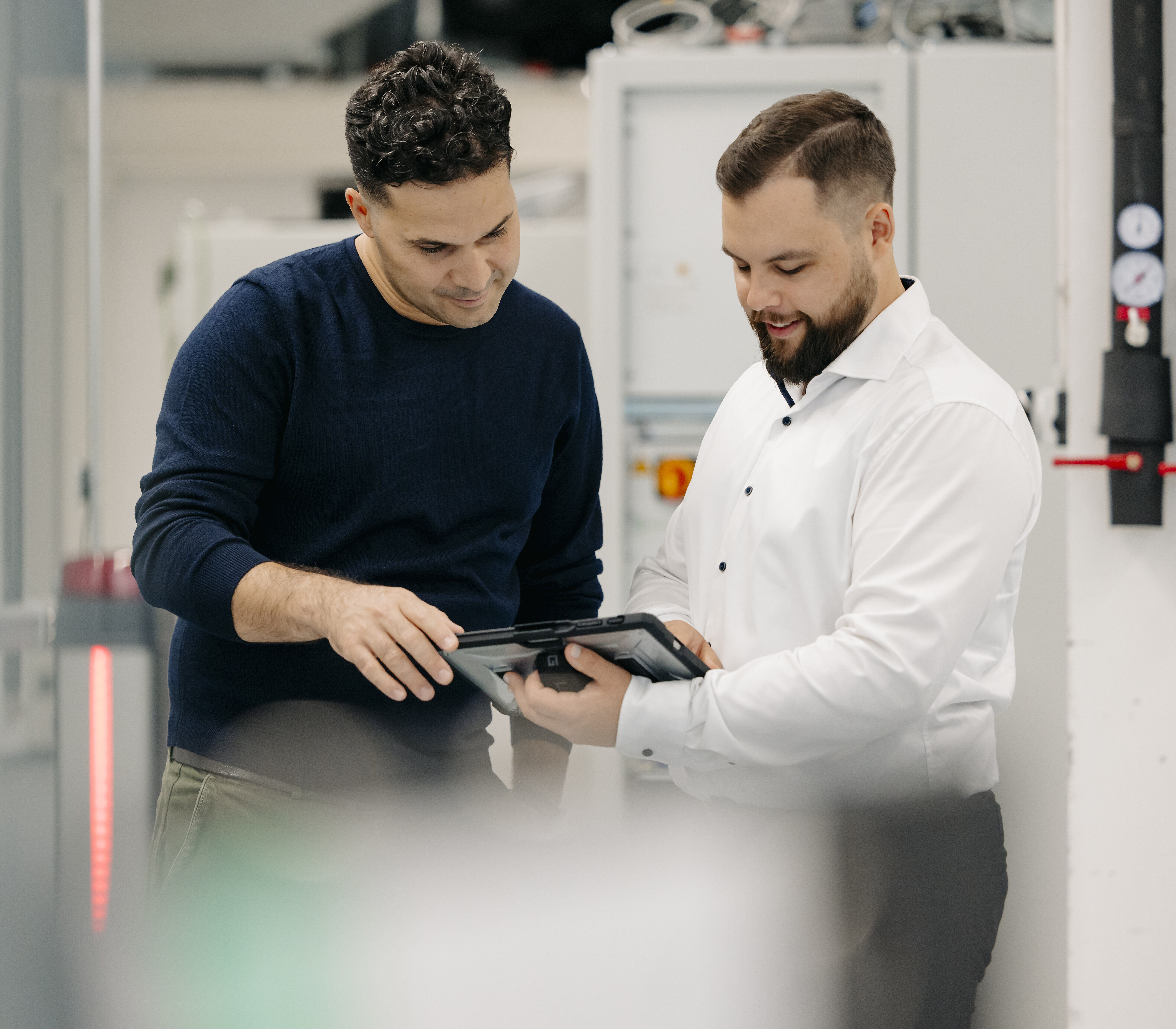 Zwei Personen in einer Fertigungsumgebung prüfen Daten auf einem Tablet.