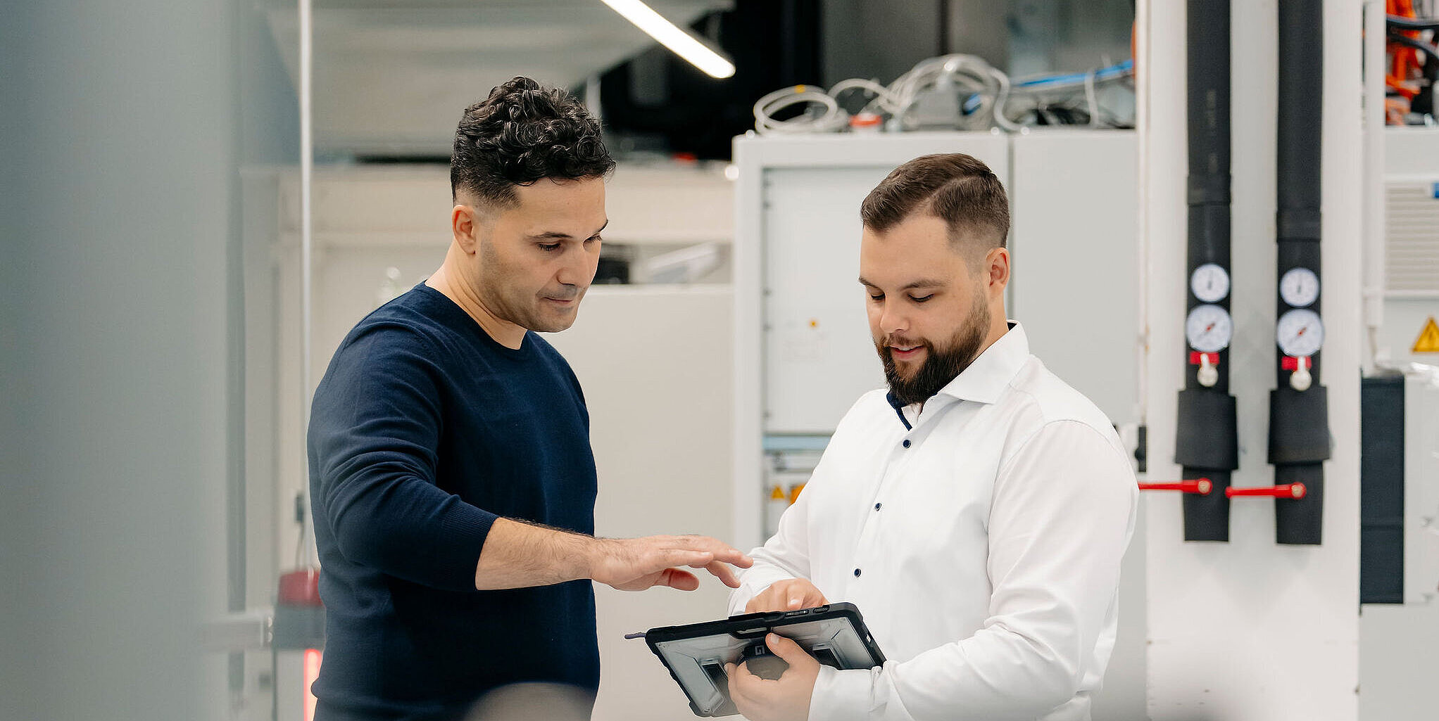 Ingenieure von Silver Atena prüfen technische Daten auf einem Tablet in einer Entwicklungsumgebung.