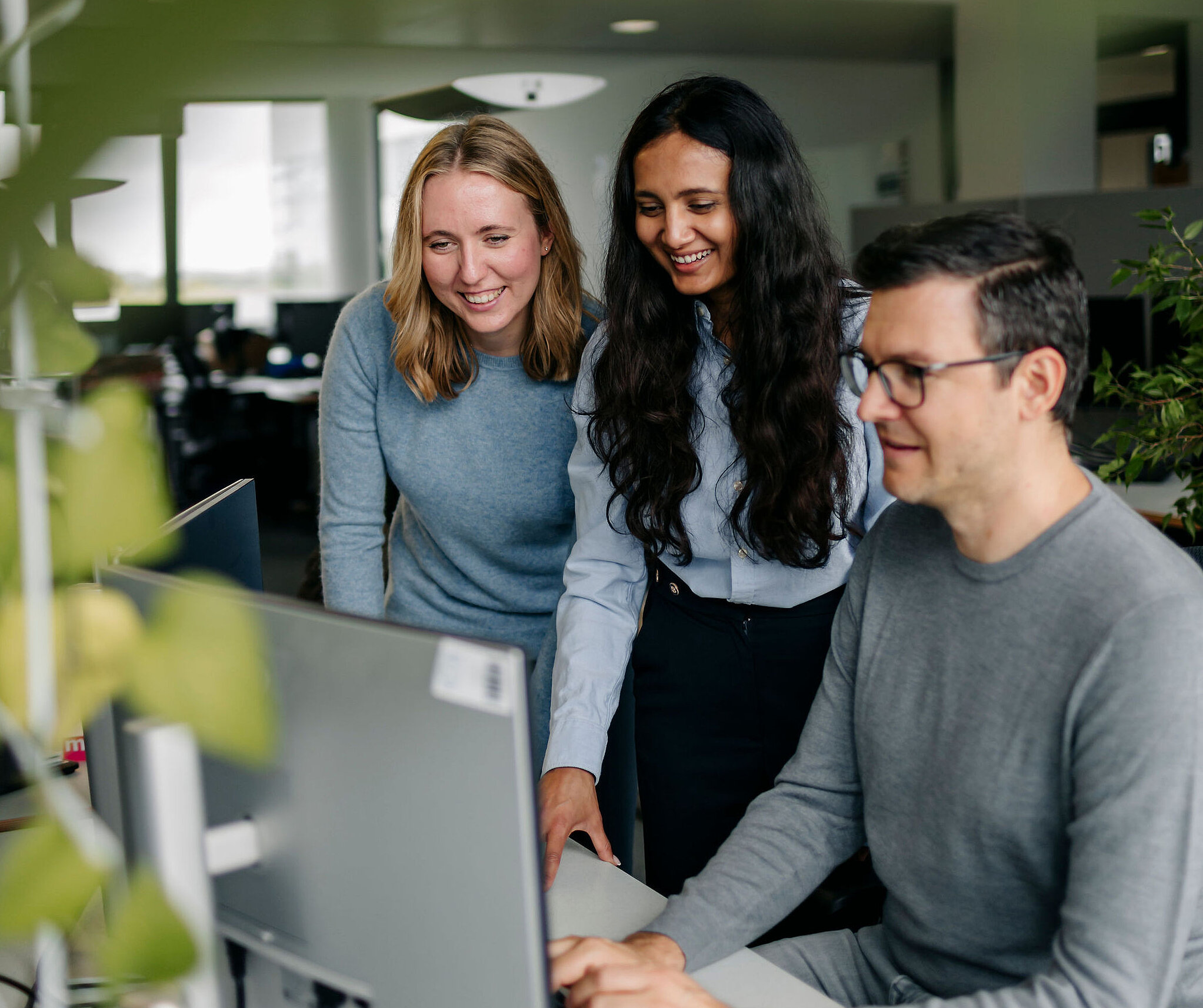 Drei Mitarbeitende von Silver Atena arbeiten gemeinsam an einem Computerarbeitsplatz und besprechen technische Projektinhalte.