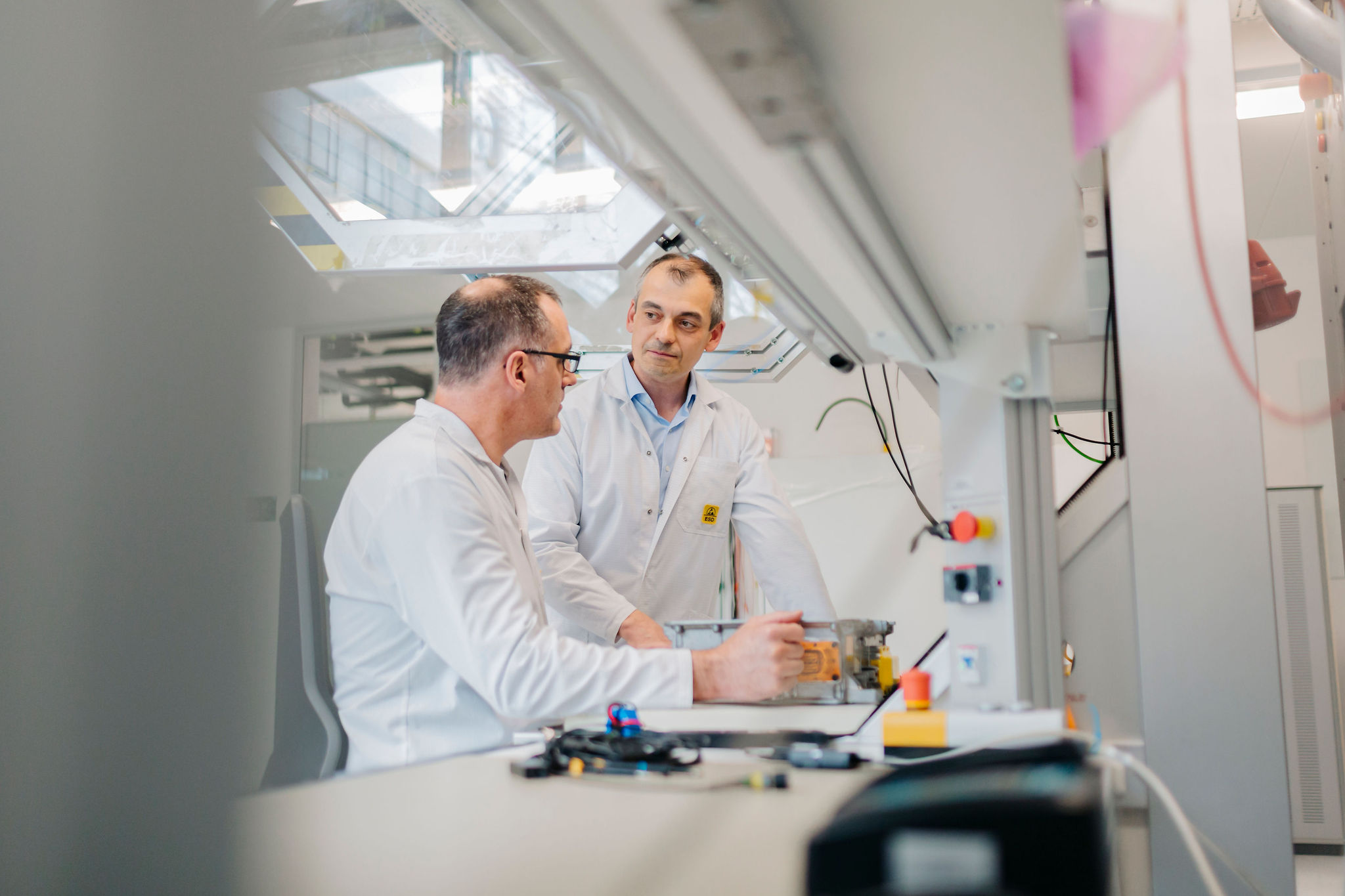 Zwei Ingenieure besprechen einen technischen Aufbau an einem Laborarbeitsplatz mit elektronischen Komponenten