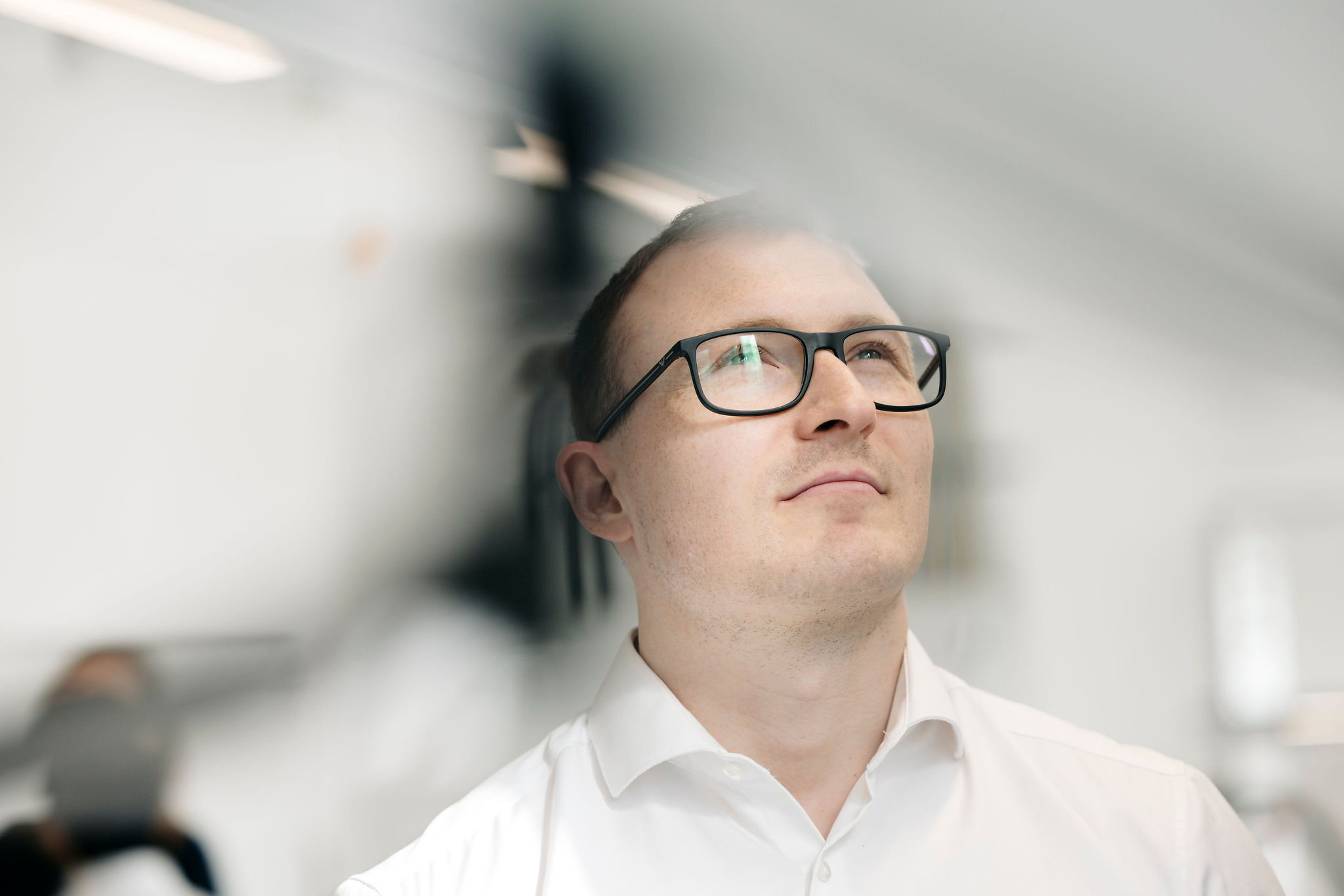 Mitarbeiter von Silver Atena mit Brille und weißem Hemd blickt konzentriert auf eine technische Anlage im Entwicklungslabor.