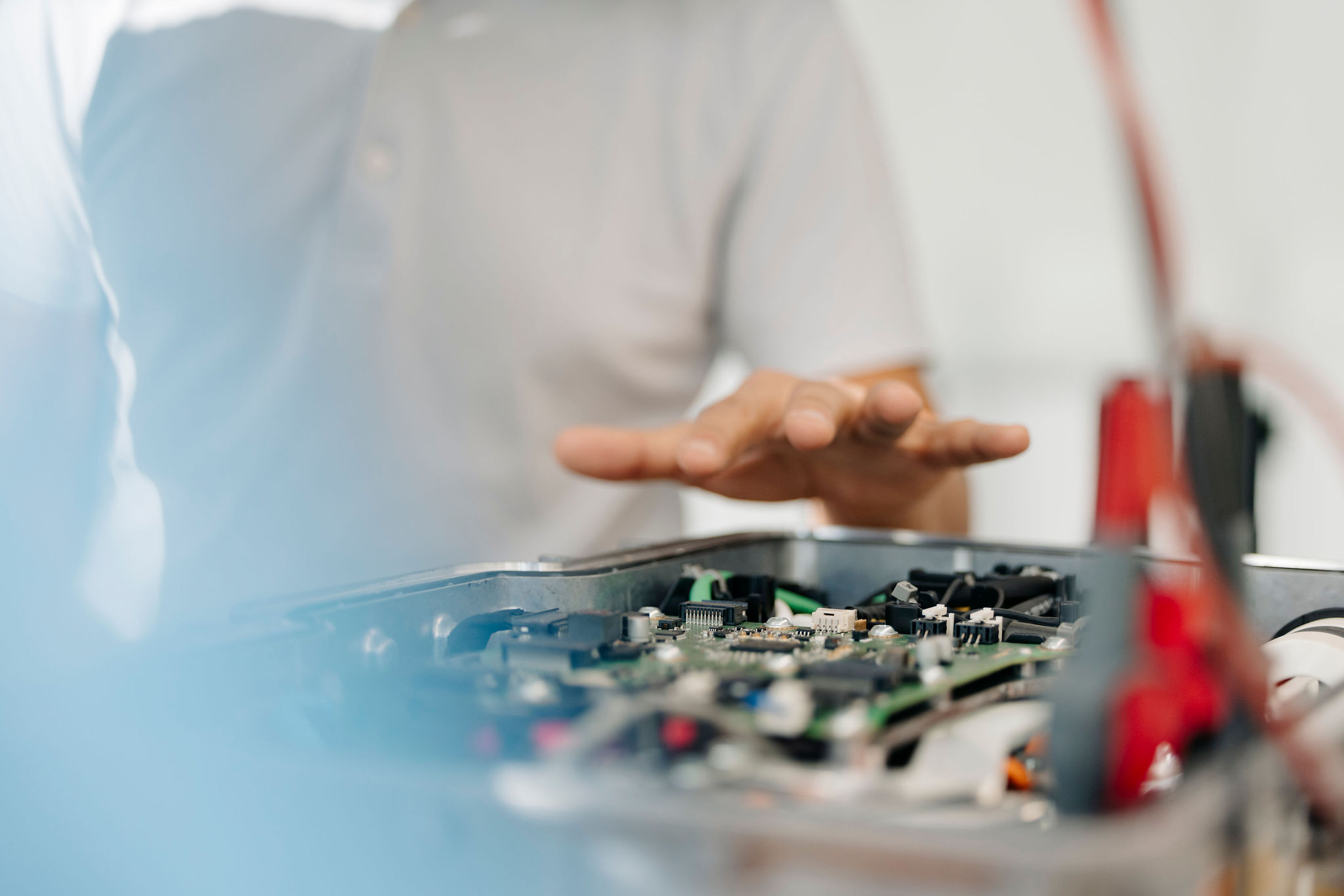 Detailaufnahme einer elektronischen Baugruppe mit Leiterplatte im geöffneten Metallgehäuse während einer technischen Besprechung.