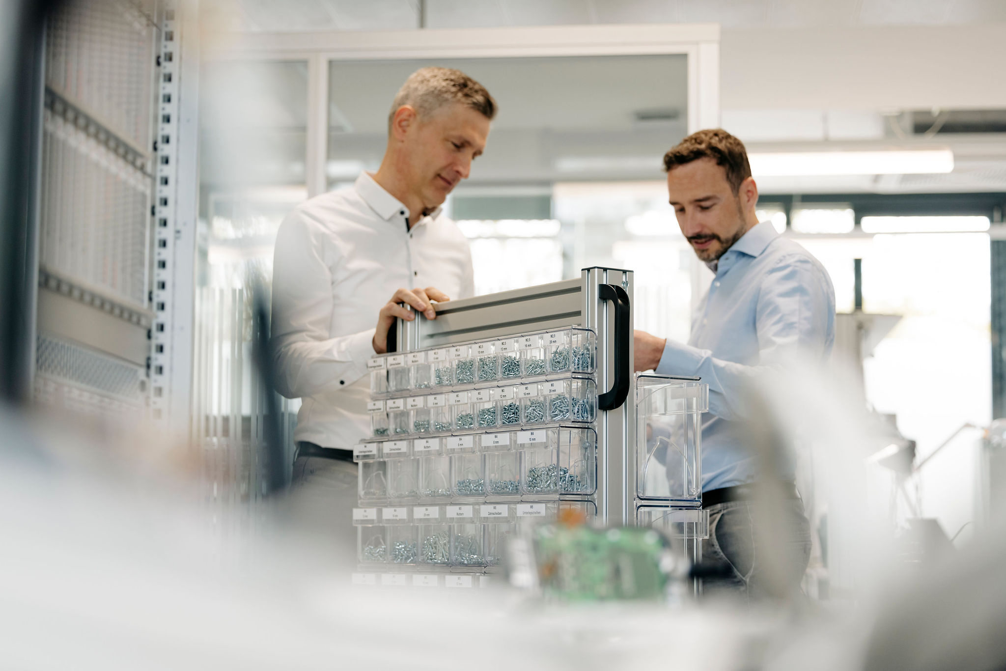 Zwei Mitarbeiter von Silver Atena besprechen technische Komponenten und Montagematerial an einem Arbeitsplatz im Entwicklungslabor.
