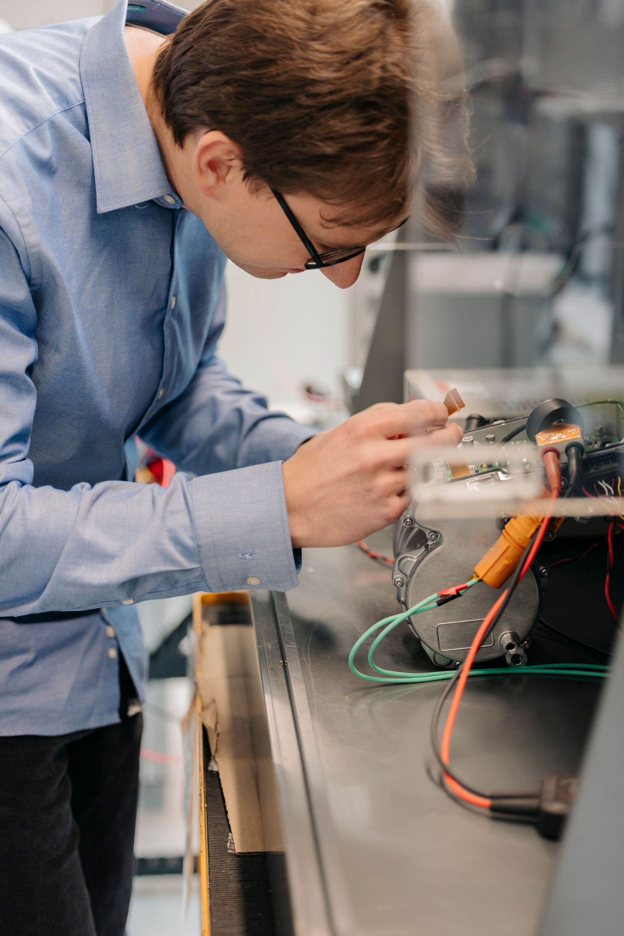 Ingenieur von Silver Atena untersucht eine elektronische Baugruppe mit Metallgehäuse und angeschlossenen Leitungen im Entwicklungslabor.