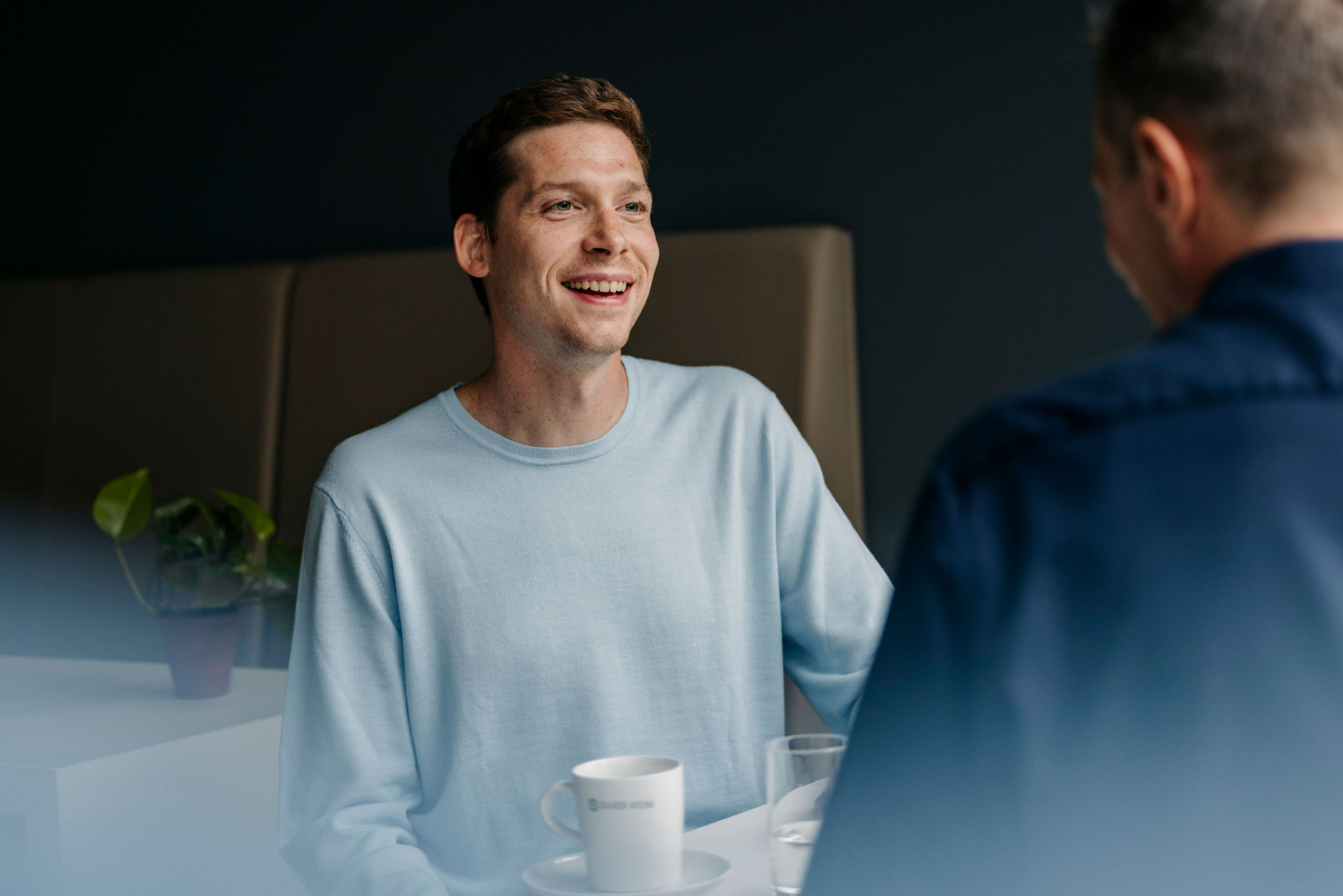 Zwei Mitarbeiter von Silver Atena unterhalten sich in entspannter Atmosphäre bei einer Tasse Kaffee im Büro.