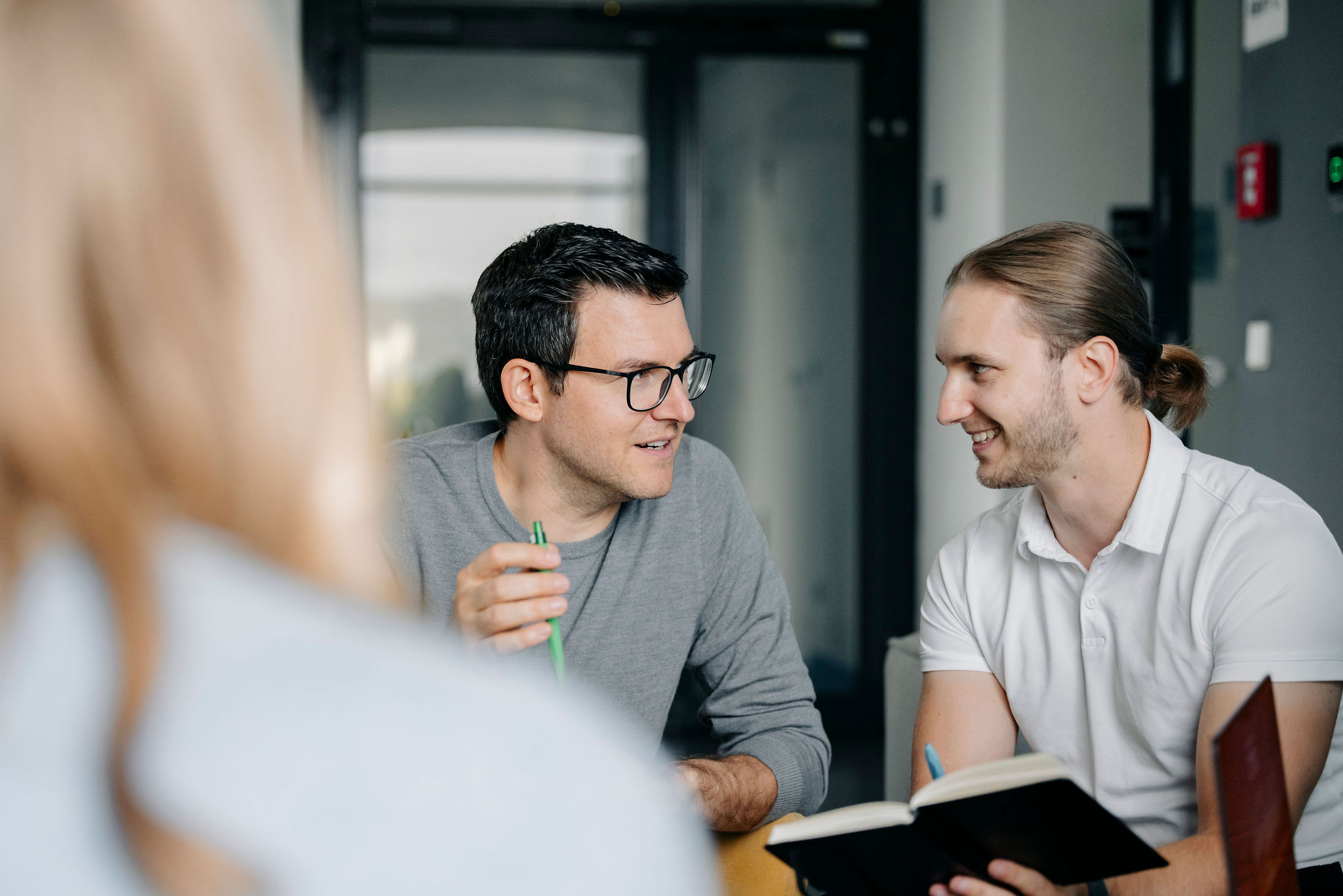 Zwei Mitarbeiter von Silver Atena besprechen technische Themen anhand eines Notizbuchs während einer Projektbesprechung.