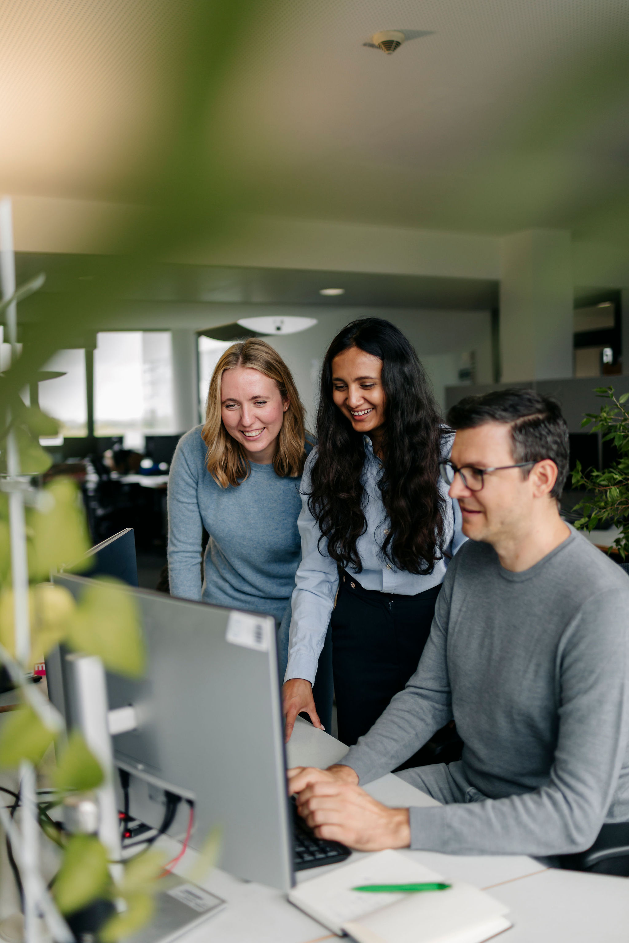 Drei Mitarbeitende von Silver Atena arbeiten gemeinsam an einem Computerarbeitsplatz und besprechen technische Projektinhalte.