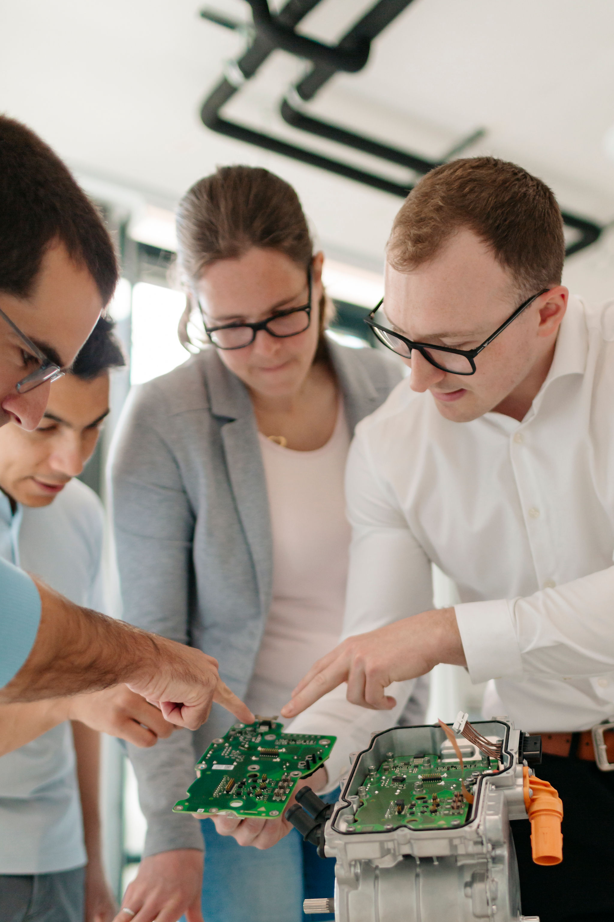 Vier Mitarbeitende von Silver Atena untersuchen elektronische Leiterplatten und deren Integration in ein geöffnetes Steuergerätegehäuse.