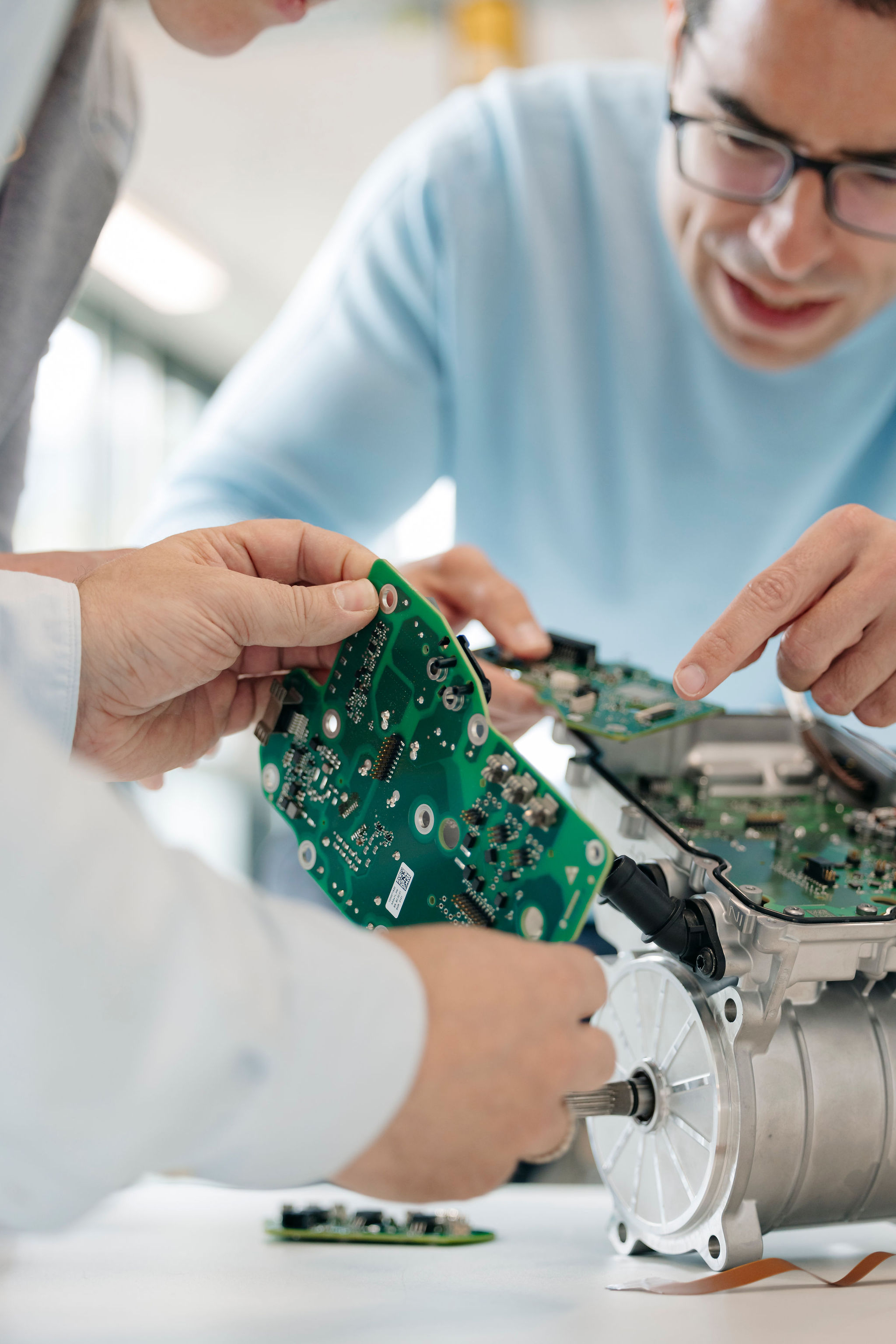 Zwei Ingenieure von Silver Atena vergleichen elektronische Leiterplatten mit einer geöffneten Antriebseinheit im Entwicklungslabor.