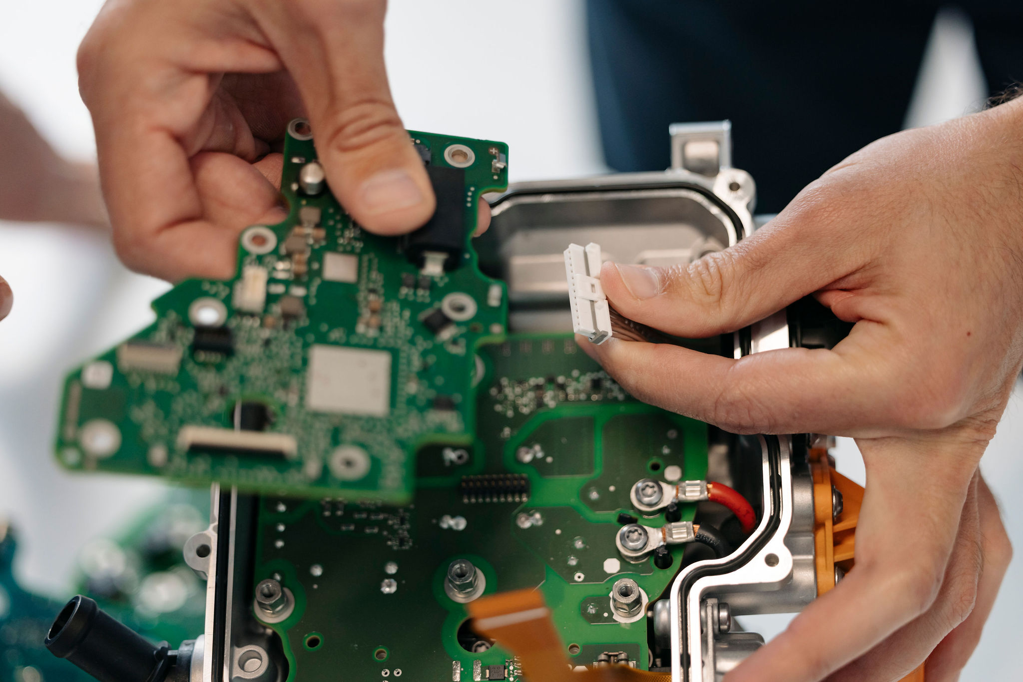 Detailaufnahme einer bestückten Leiterplatte und eines Steckverbinders beim Zusammenbau eines elektronischen Steuergeräts.