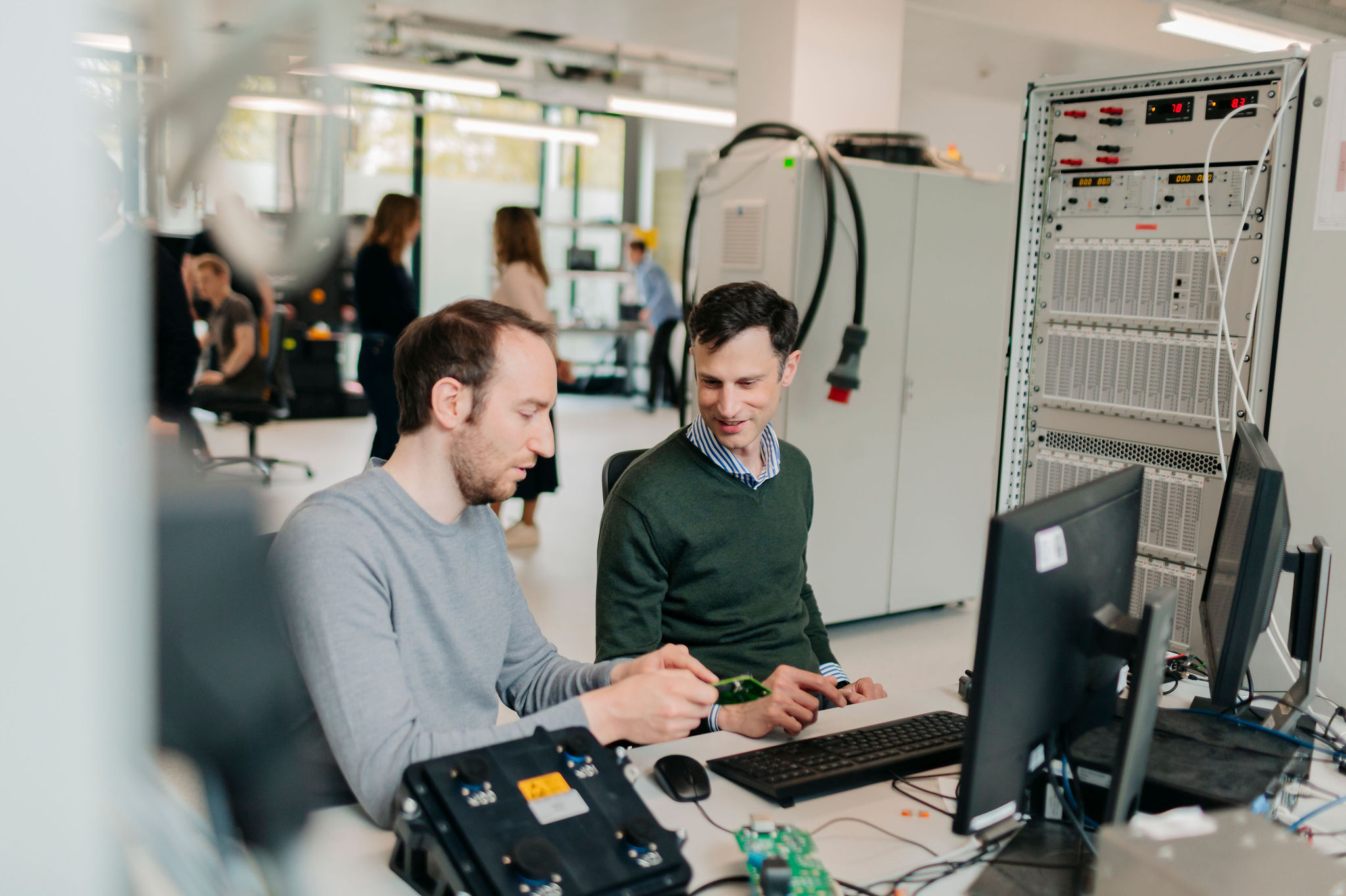 Zwei Ingenieure von Silver Atena besprechen die Systemintegration einer elektronischen Baugruppe an einem Computerarbeitsplatz.