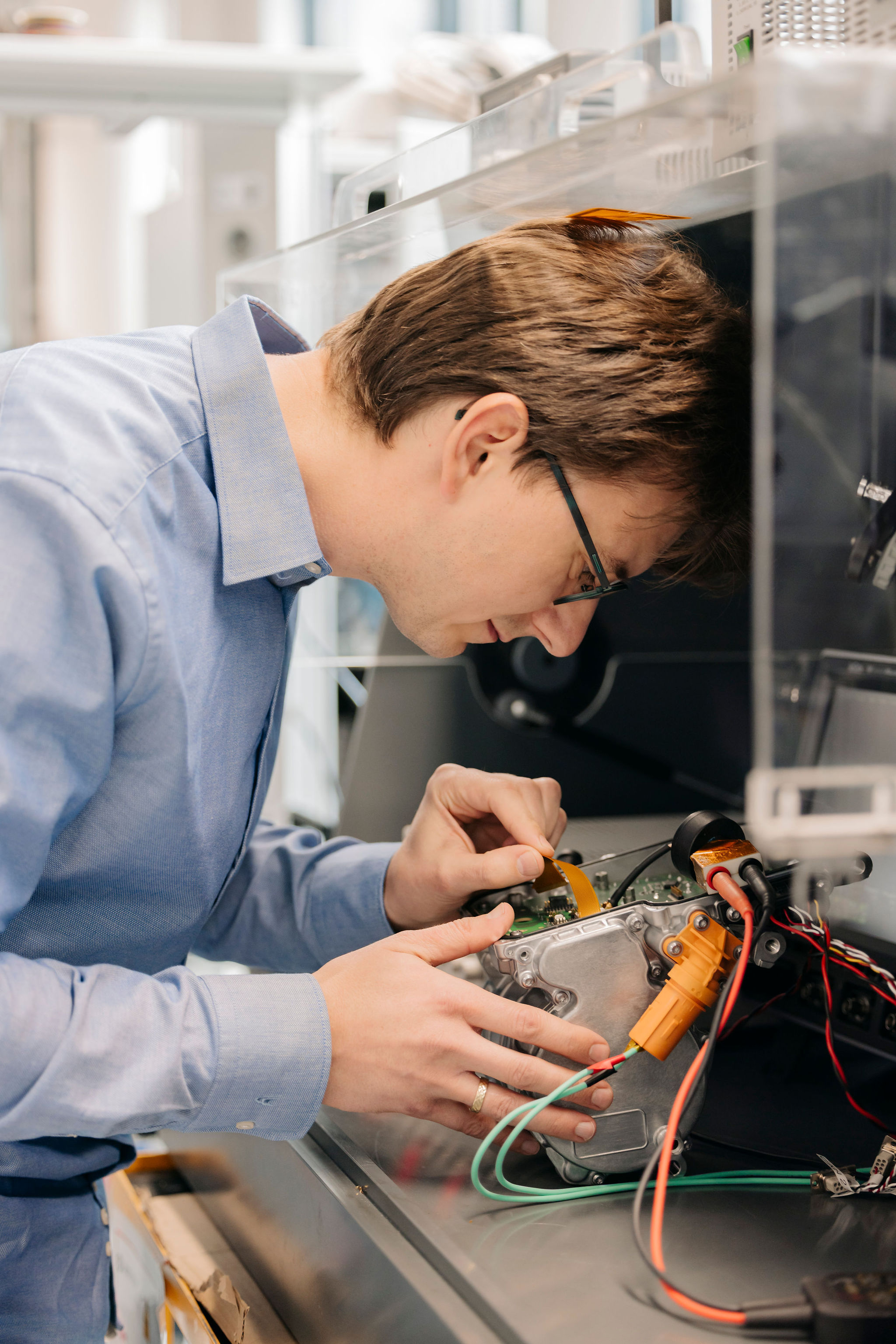 Ingenieur von Silver Atena untersucht eine elektronische Baugruppe mit geöffnetem Metallgehäuse und angeschlossenen Leitungen.