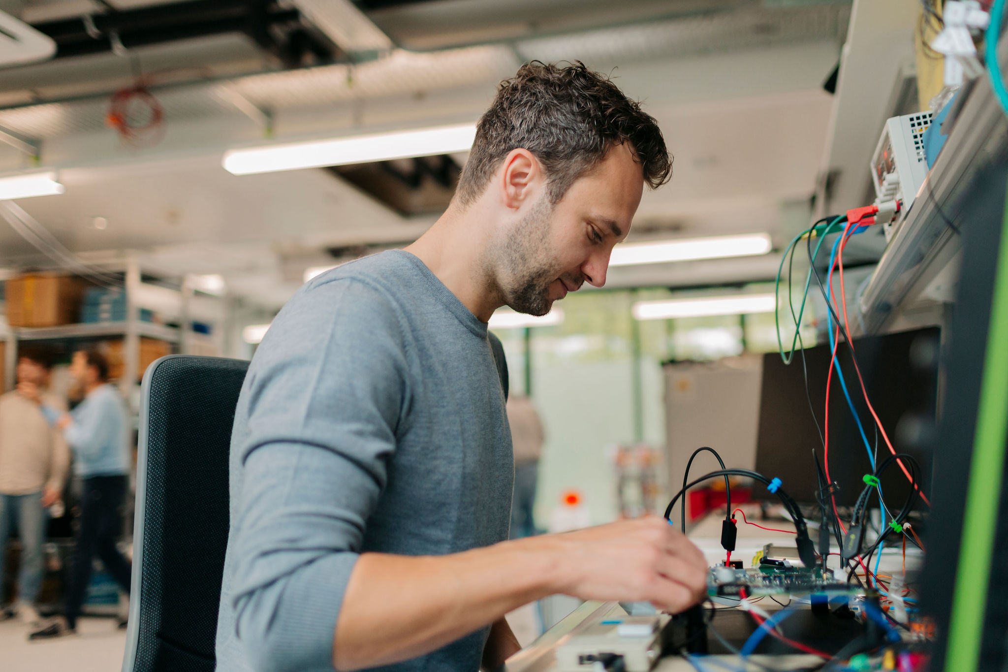 Person arbeitet an einer elektronischen Baugruppe an einem Entwicklungsarbeitsplatz.
