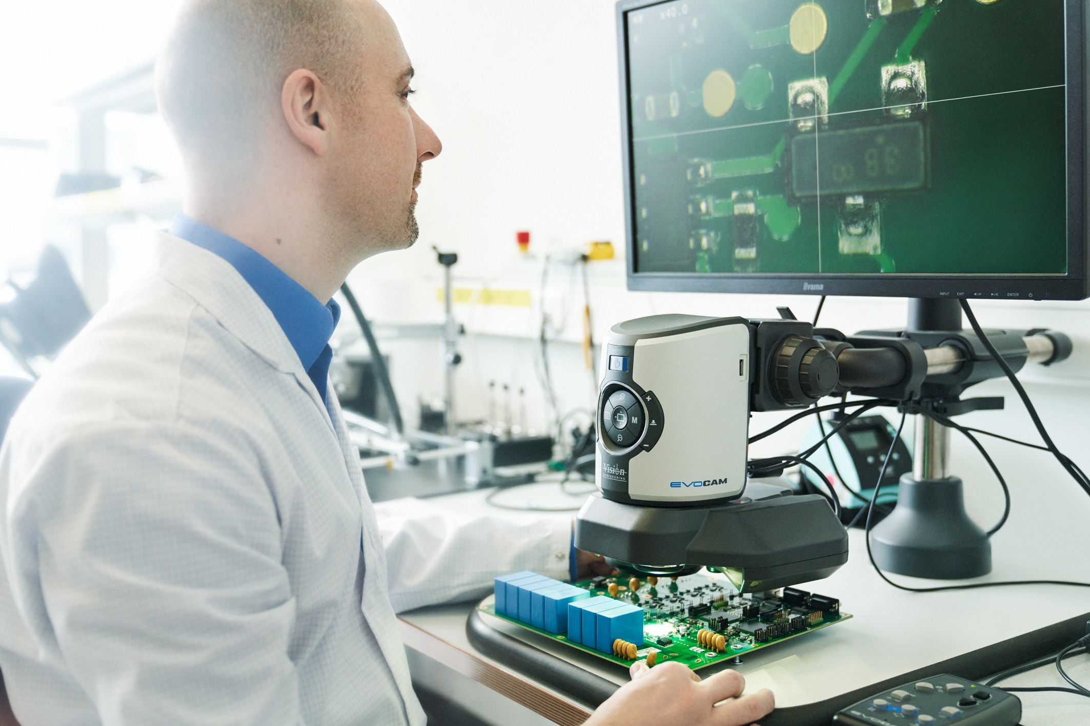 Leiterplatte unter einem Mikroskop mit vergrößerter Darstellung auf einem Bildschirm.
